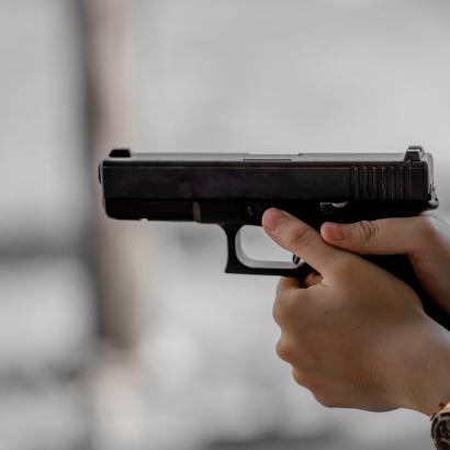 Close-up of a handgun aimed at a distant bullseye target in a wide Berlin indoor range
